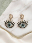 Pair of evil eye drop earrings on marble surface showing full front view of rhinestone detailing