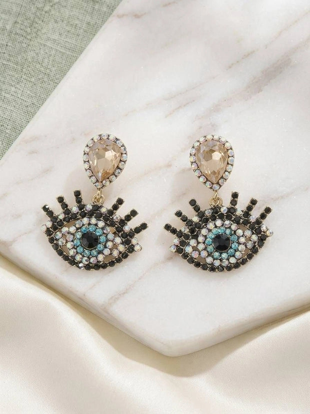 Pair of evil eye drop earrings on marble surface showing full front view of rhinestone detailing