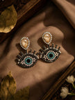 Evil eye rhinestone drop earrings displayed on brown satin with dried leaves and white flowers