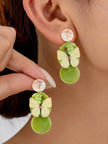 Model wearing olive green resin butterfly drop earrings with peach marble stud tops on ear