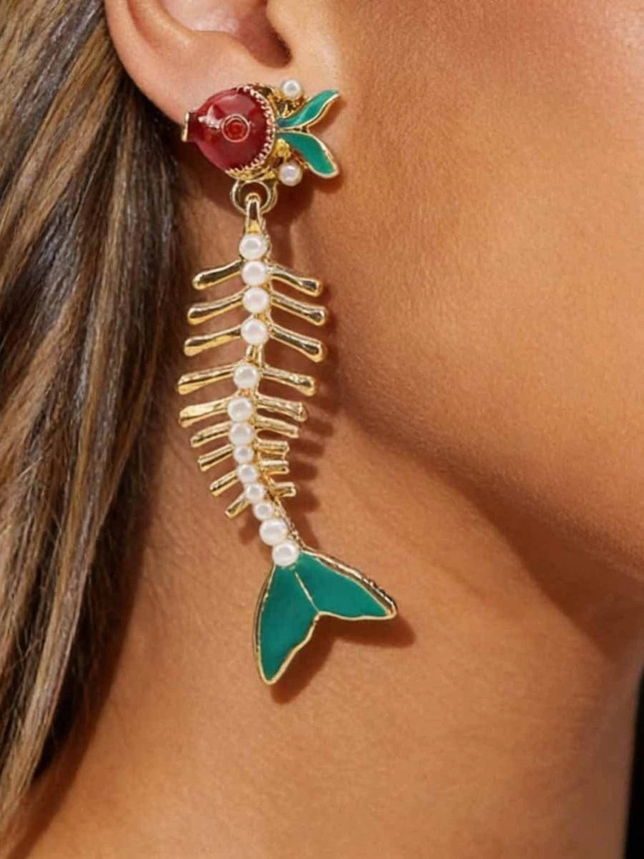 Gold-plated fish skeleton drop earring with red enamel head and teal tail worn on ear
