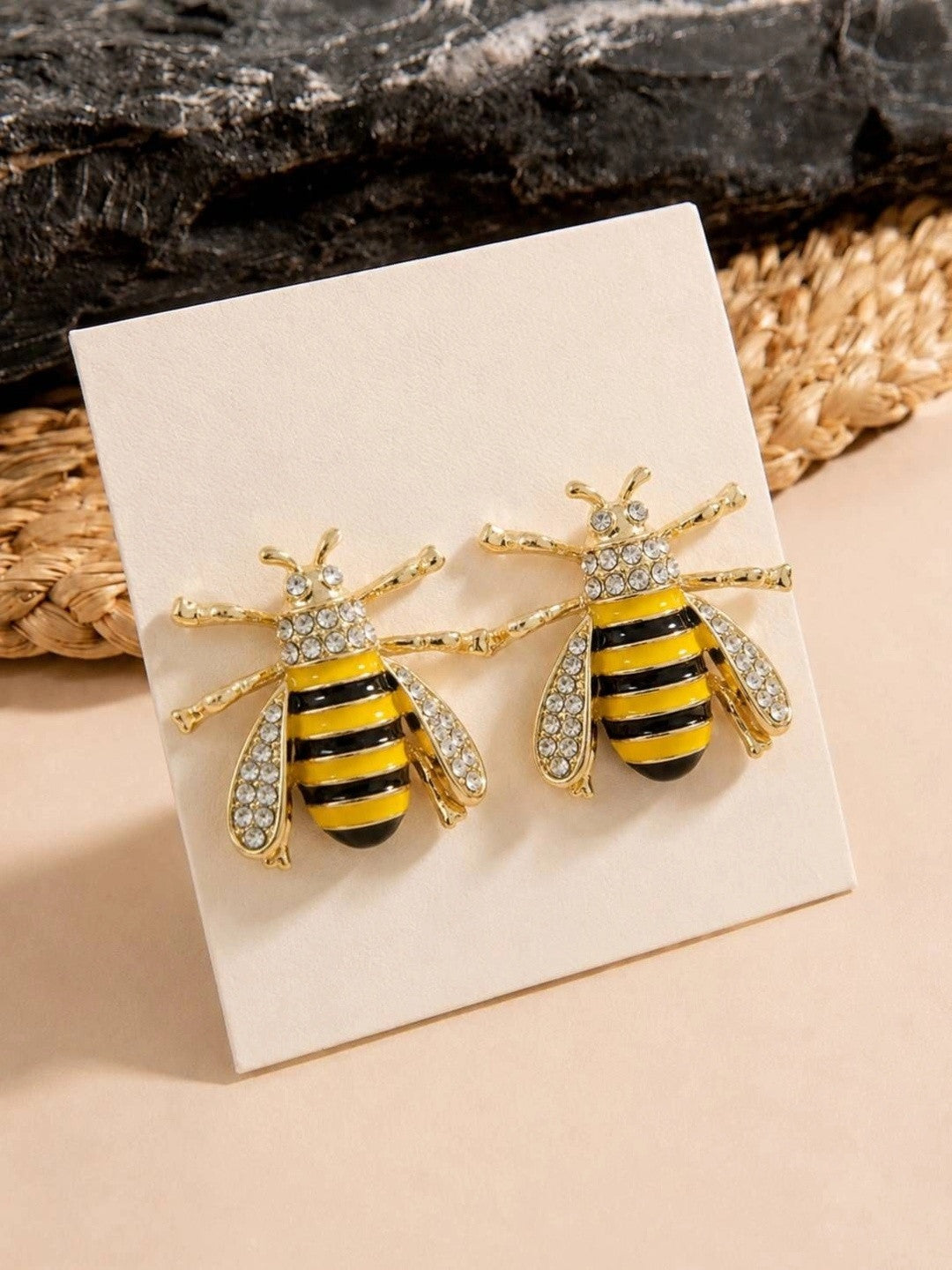 Pair of gold-toned bee stud earrings with yellow black enamel and crystal wings on a white jewellery card