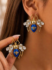 Woman wearing gold-plated cobalt blue enamel beetle stud earrings with crystal wings, one earring held up close