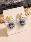 Two gold and blue beetle stud earrings displayed upright on a white jewellery card