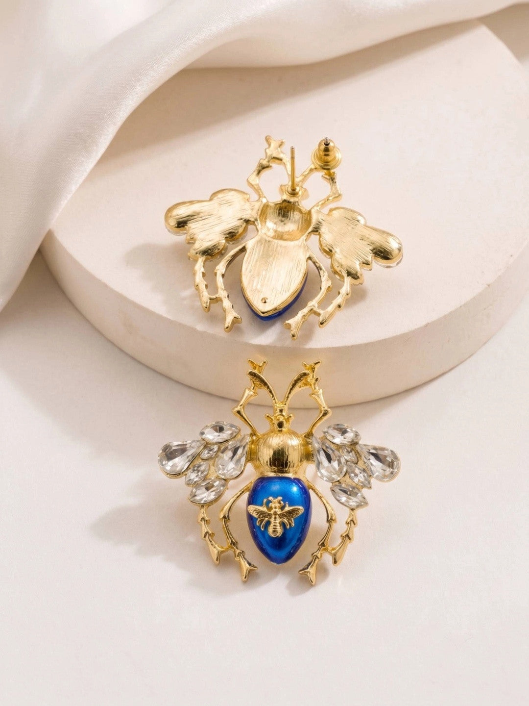 Back and front view of blue enamel beetle earrings showing push-back stud closure and gold detailing