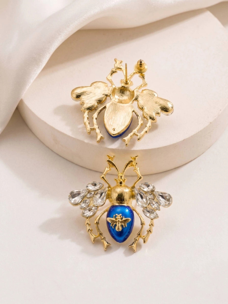 Back and front view of blue enamel beetle earrings showing push-back stud closure and gold detailing