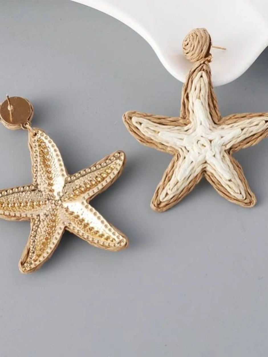 Two starfish drop earrings side by side — one gold-tone metal, one woven rattan in beige and white, on grey background