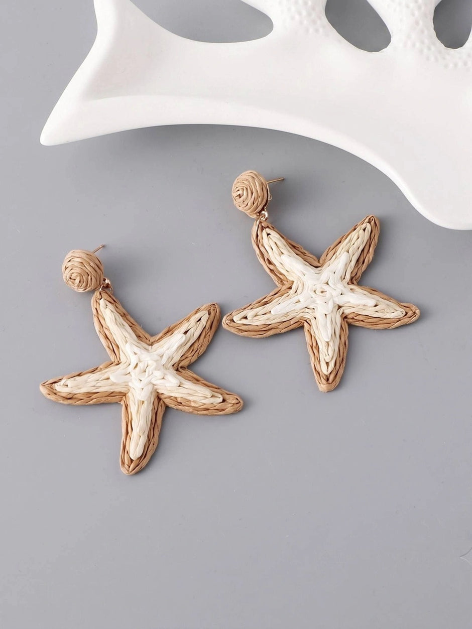 Pair of woven rattan starfish drop earrings with coiled stud tops displayed flat on grey surface