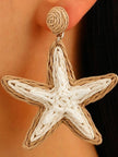 Close-up of woven rattan starfish drop earring worn on a model's ear showing beige and white cord detail