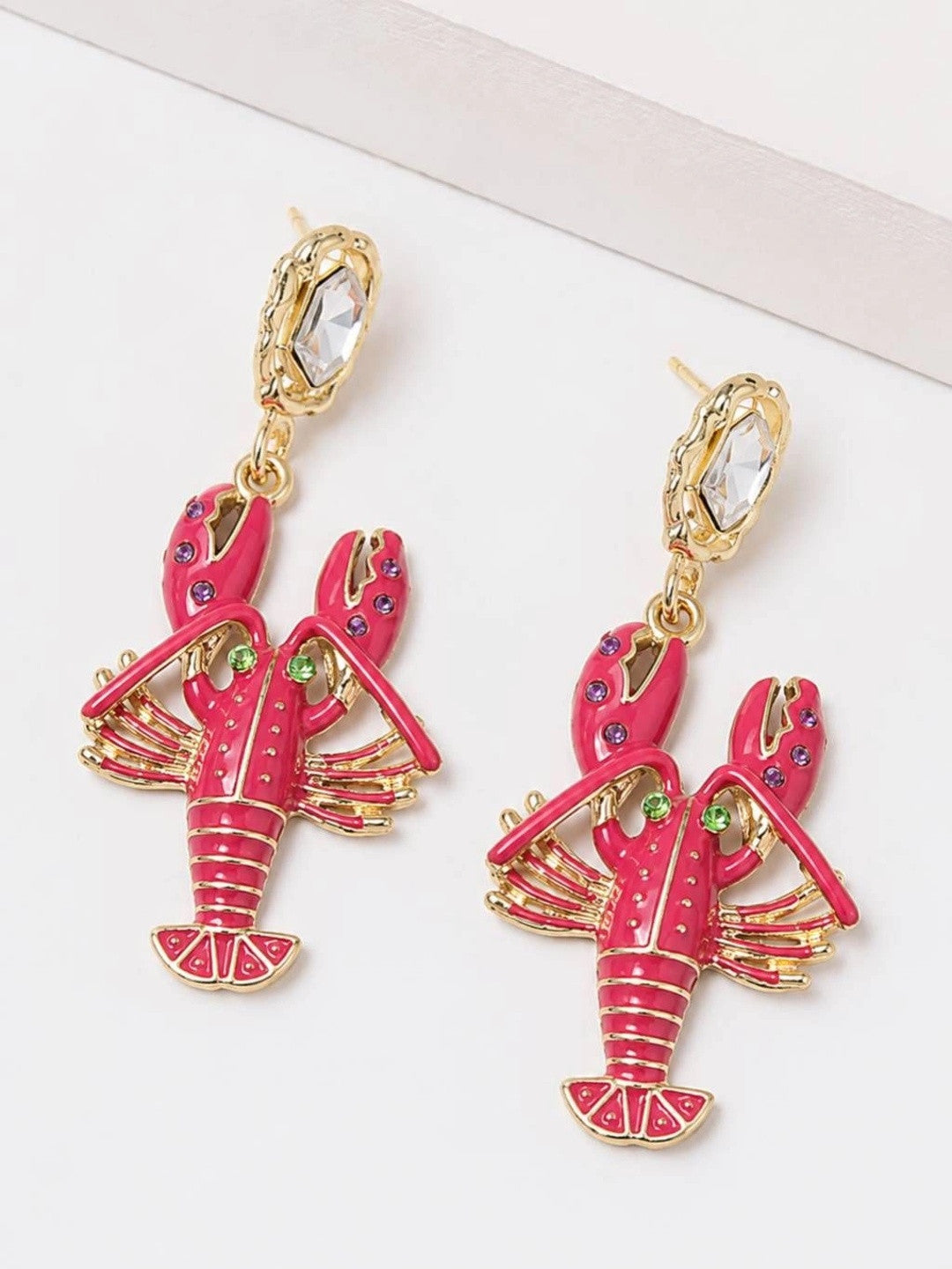 Close-up of both lobster earrings showing pink, green, and purple rhinestone details on fuchsia enamel body