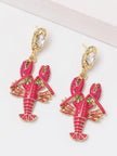 Close-up of both lobster earrings showing pink, green, and purple rhinestone details on fuchsia enamel body