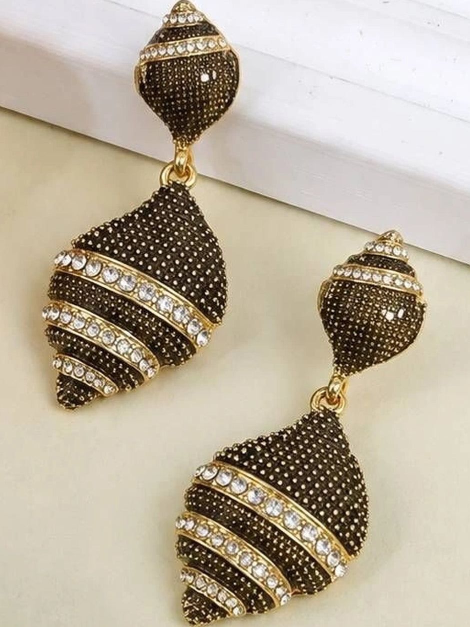 Two oxidised gold geometric drop earrings displayed apart on cream surface showing detail