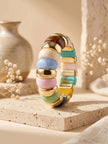 Multicolour resin stretch bracelet standing upright on a travertine tile with dried flowers in background