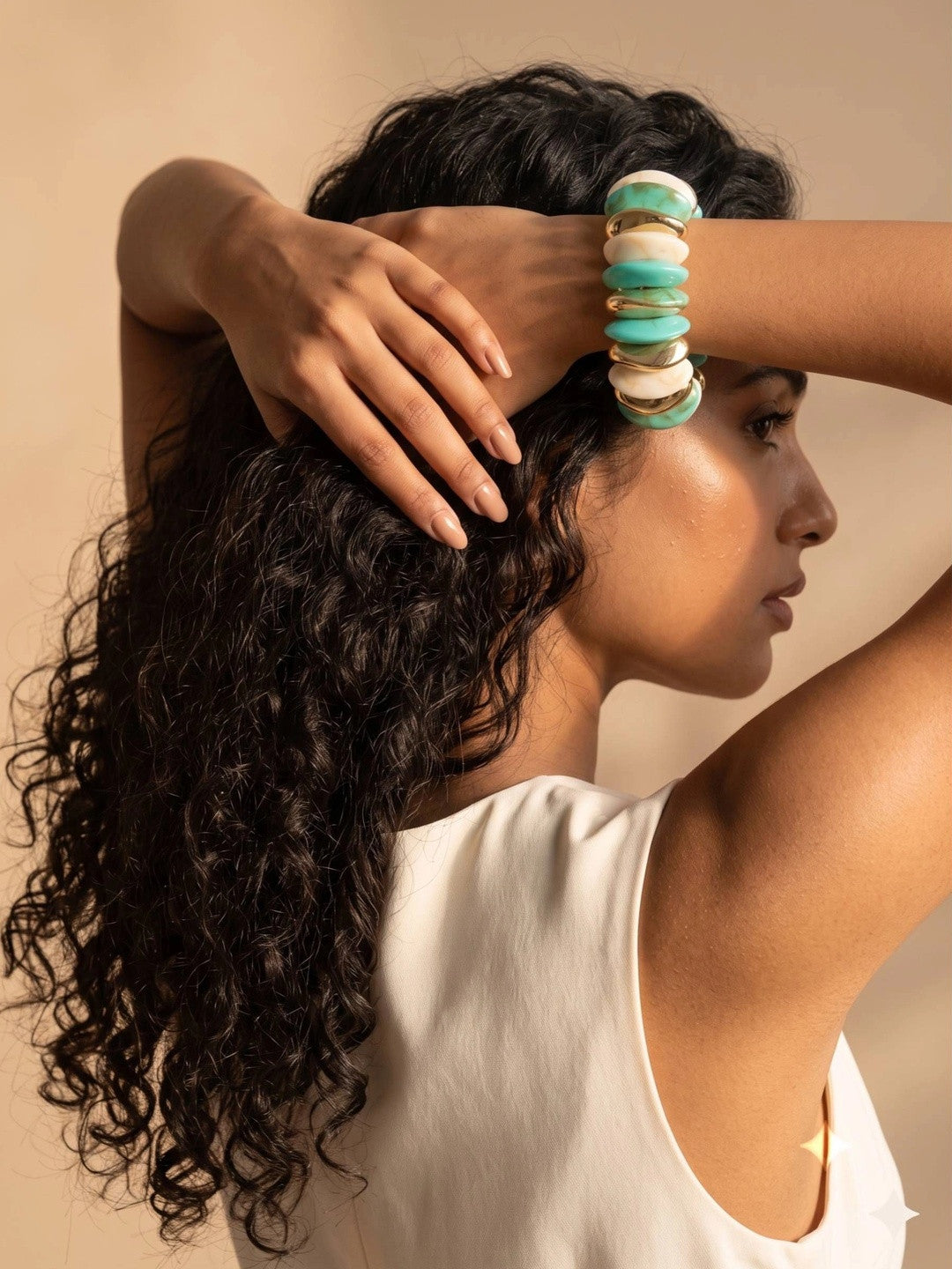 Woman with curly hair wearing turquoise marble resin cuff bracelet on her wrist raised behind her head