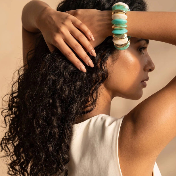 Woman with curly hair wearing turquoise marble resin cuff bracelet on her wrist raised behind her head
