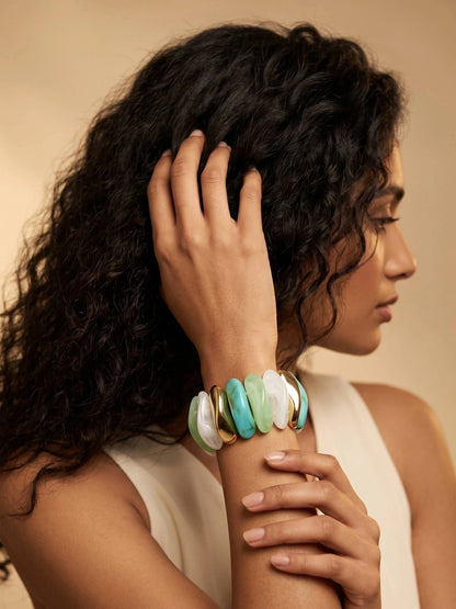 Model wearing resin stretch bracelet with multicolour links on her wrist against a warm beige studio background