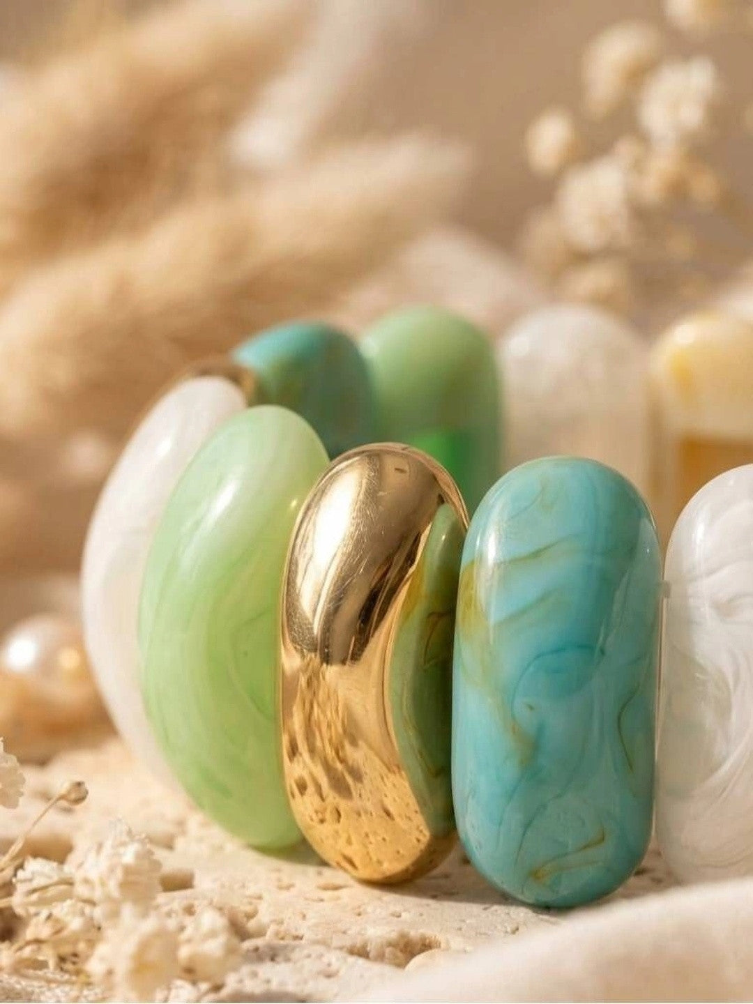 Close-up of polished gold-tone connector between mint green and turquoise resin links of the stretch bracelet