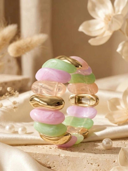 Close-up side view of pastel resin stretch bracelet showing layered bead arrangement on white surface