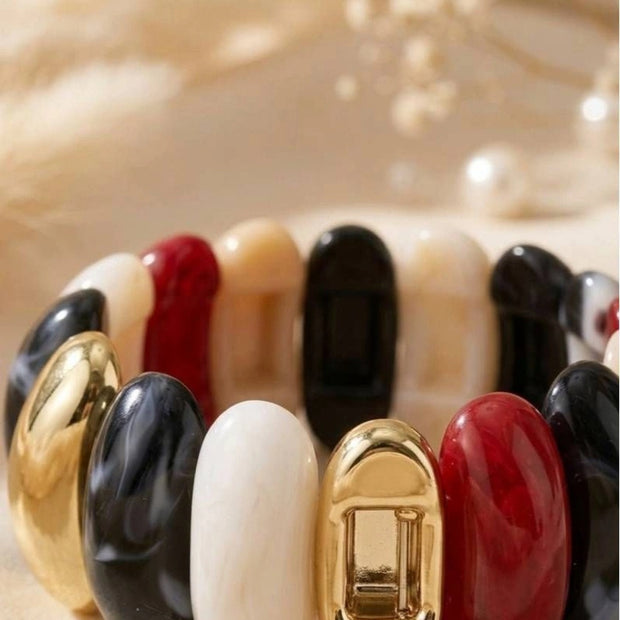 Close-up of multicolour resin cuff bracelet showing gold-toned clasp and glossy red, black, white, and marbled oval segments