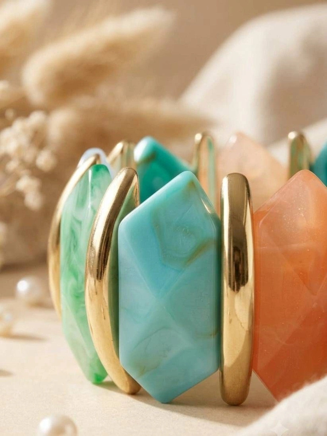 Close-up of teal, mint and peach faceted resin panels separated by polished gold-tone metal bars