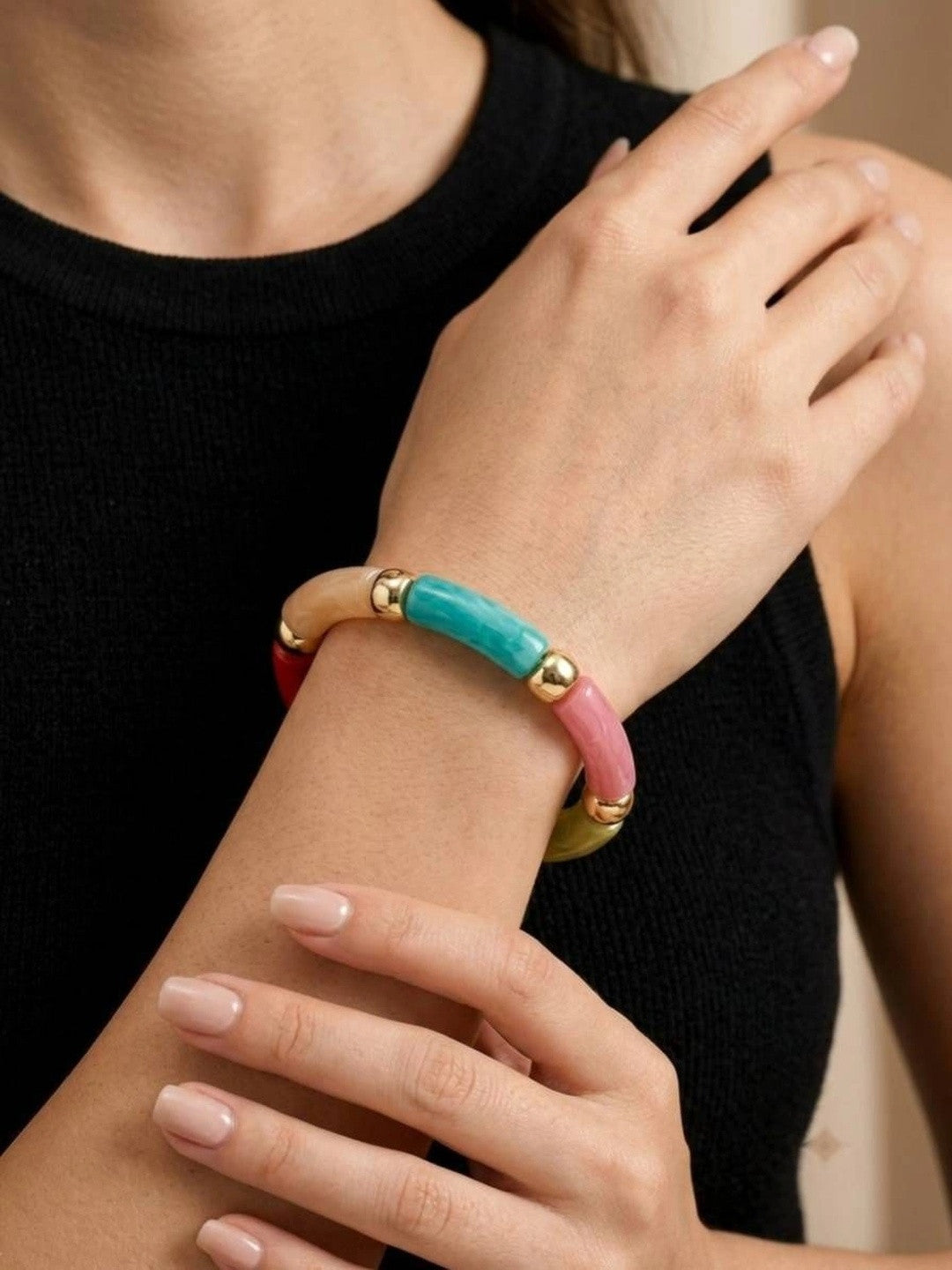 Multicolour resin tube bracelet worn on a woman's wrist over a black knit top