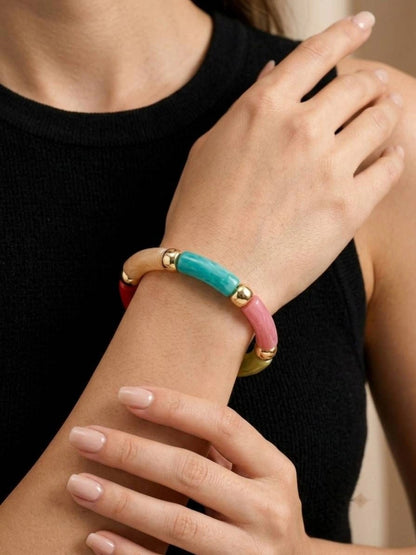 Multicolour resin tube bracelet worn on a woman's wrist over a black knit top