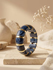 Navy blue marble resin bracelet standing upright on a travertine tile surface styled with dried gypsophila and a ceramic vase