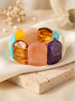 Multicolour chunky resin stretch bracelet laid flat on white silk cloth atop a travertine block with dried flowers in background
