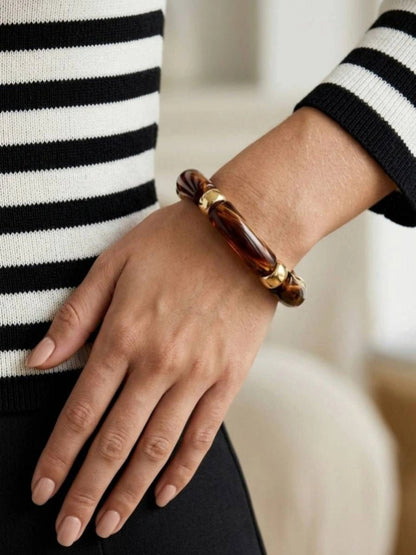 Tortoise resin stretch bracelet worn on a wrist modelled with a black and white striped knit sweater