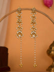 Pair of gold-plated kundan chandbali earrings with pearl chain drops hanging on a wooden display stand