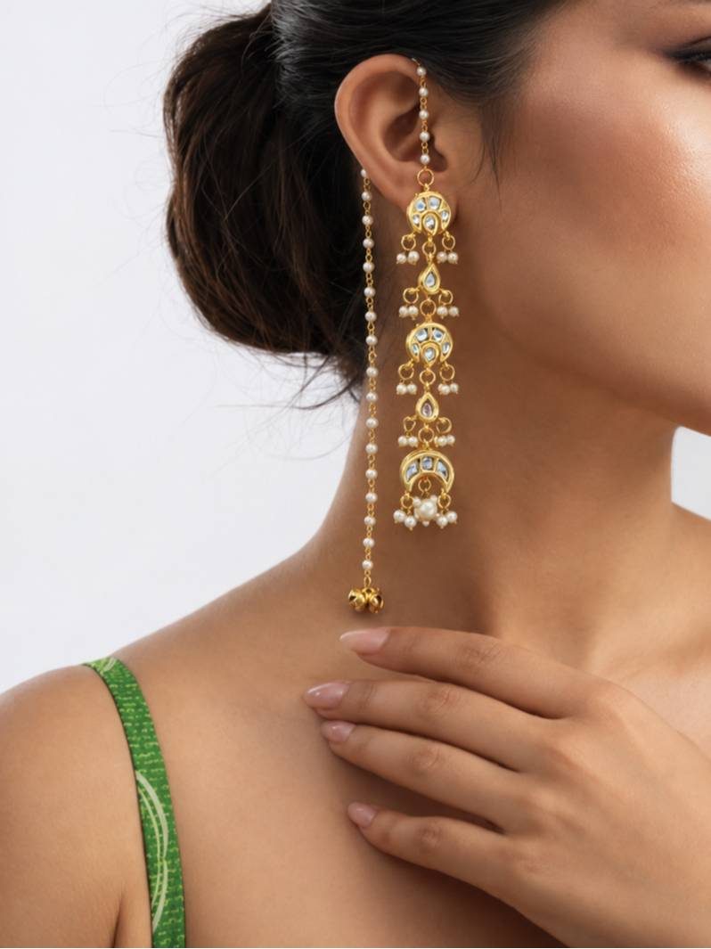 Woman wearing a gold kundan chandbali ear-cuff earring with long pearl drop against a white background