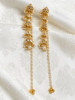 Gold-plated kundan chandbali earrings with pearl chain and bead tassel placed on white brocade fabric