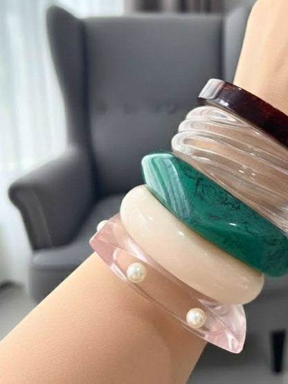 All five resin marble bangles worn together on a wrist showing scale and layered styling