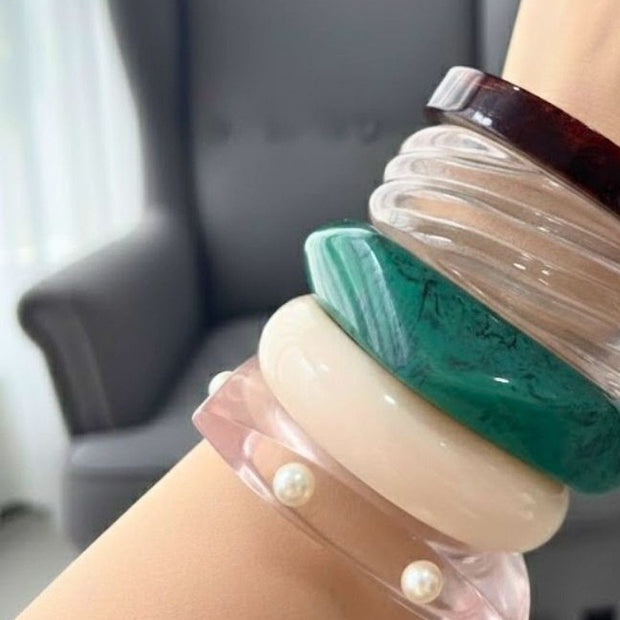 All five resin marble bangles worn together on a wrist showing scale and layered styling