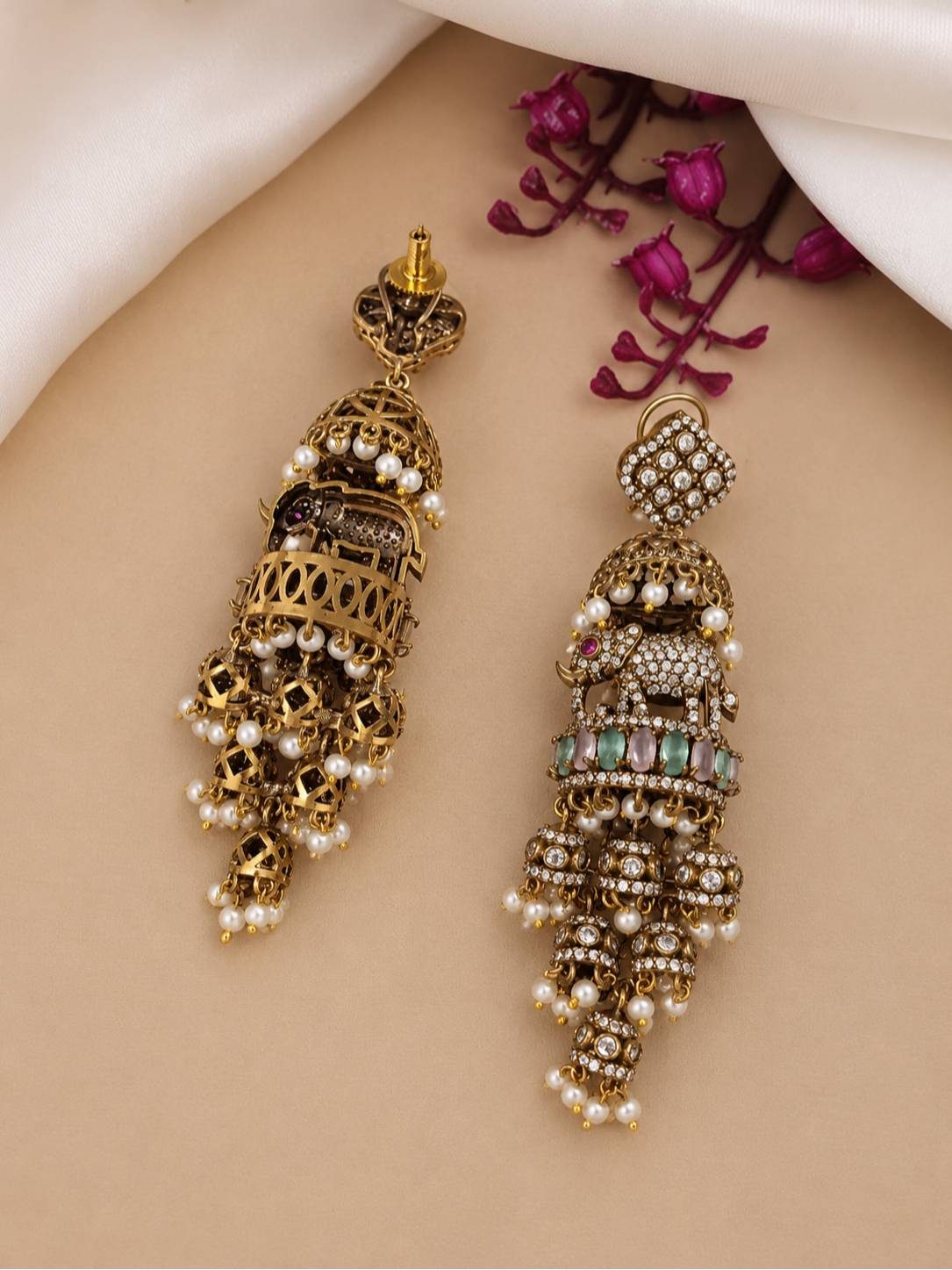 Front and back view of oxidised gold elephant jhumka earrings on beige surface revealing filigree reverse side and push-back stud fitting