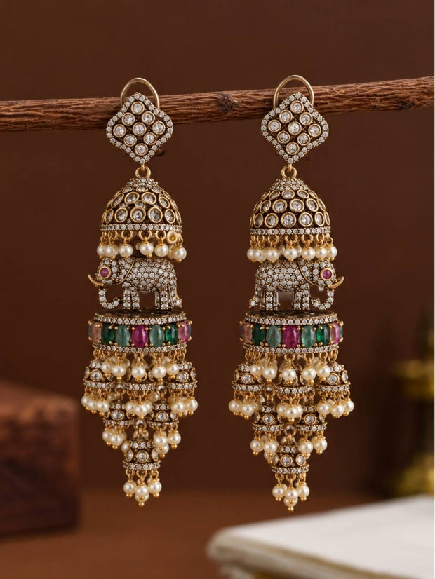 Pair of antique gold elephant jhumka earrings hanging from a wooden branch showing front detail