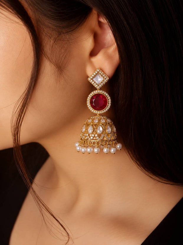 Gold-plated kundan ruby jhumka earring worn on a woman's ear showing full drop length against dark background