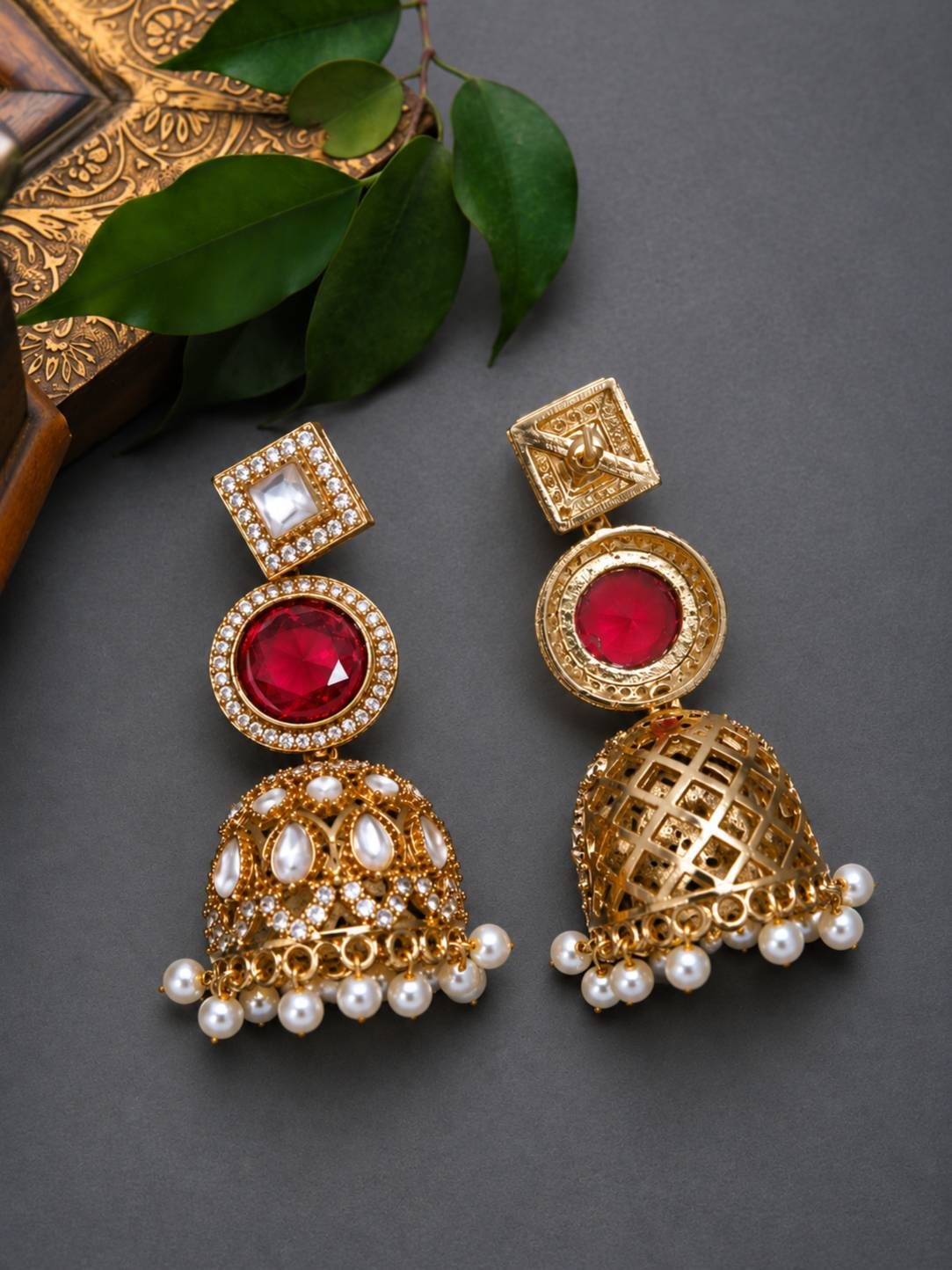 Front and back view of gold-plated kundan jhumka earrings with ruby stone on grey background
