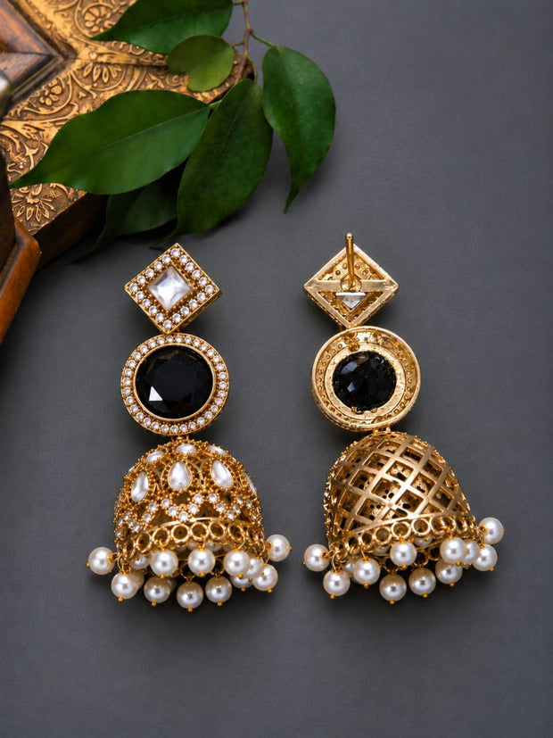 Front and back view of gold-plated kundan jhumkas displayed upright against dark grey background with green leaves