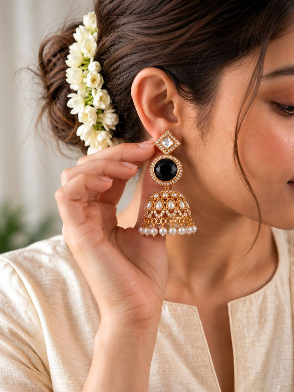 Woman wearing a single gold-plated black stone kundan jhumka with jasmine flowers in her hair
