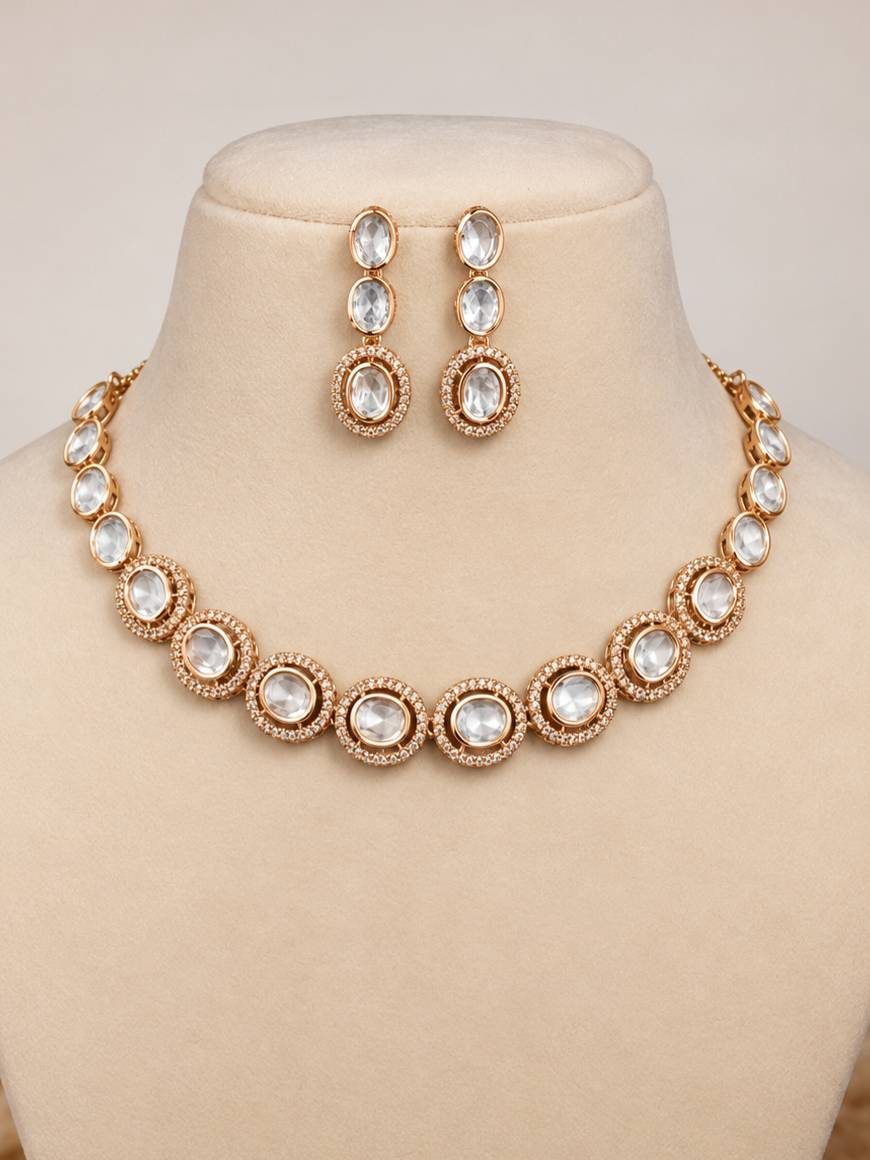 Rose gold kundan necklace set displayed on a cream jewellery bust with matching drop earrings