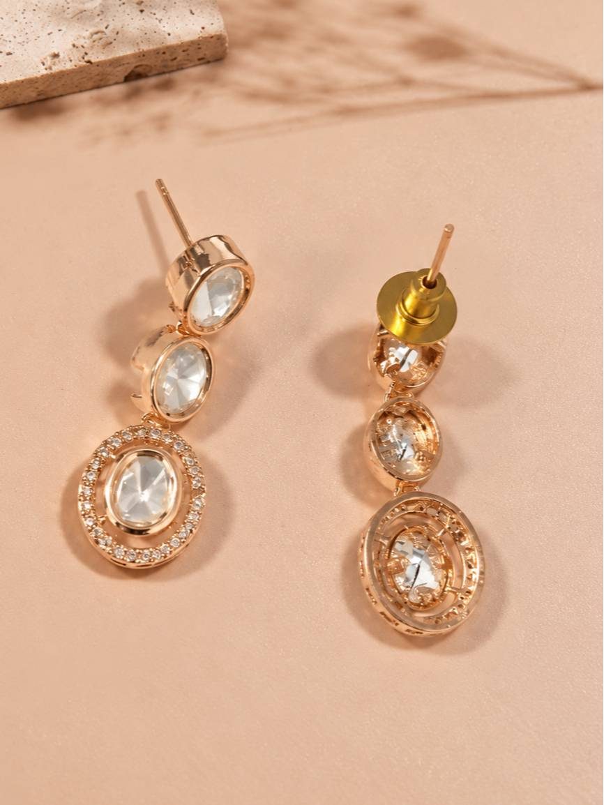 Close-up of rose gold kundan drop earrings showing three oval stones and micro-pave halo detail