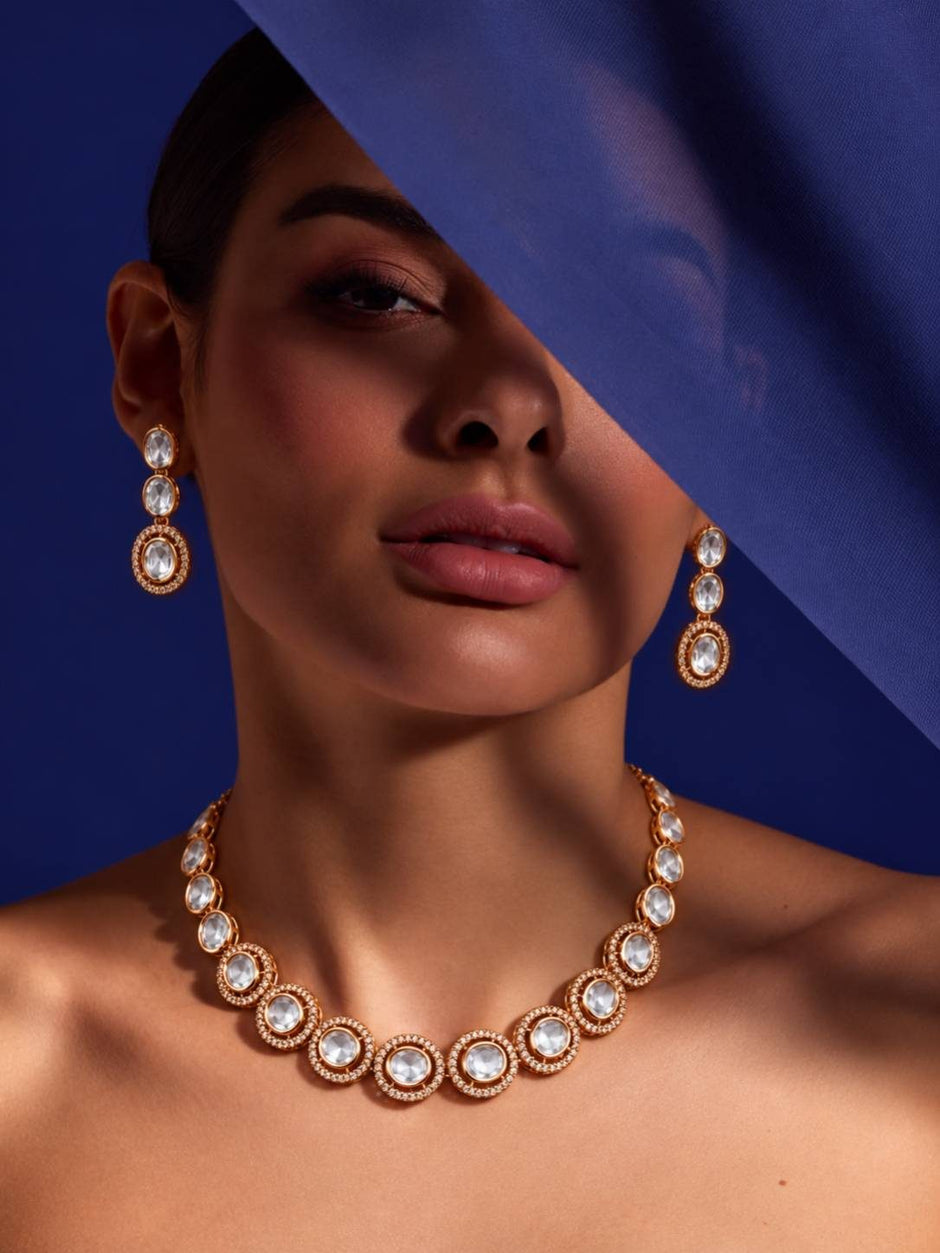 Model wearing rose gold kundan necklace set against a blue draped fabric background