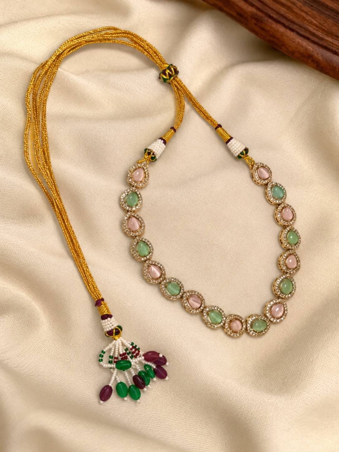 Gold-plated pink and green stone choker necklace laid flat showing adjustable gold dori tie-back closure with beaded tassel