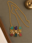 Flat lay of gold-plated raw stone pendant necklace with long rolo chain on grey surface