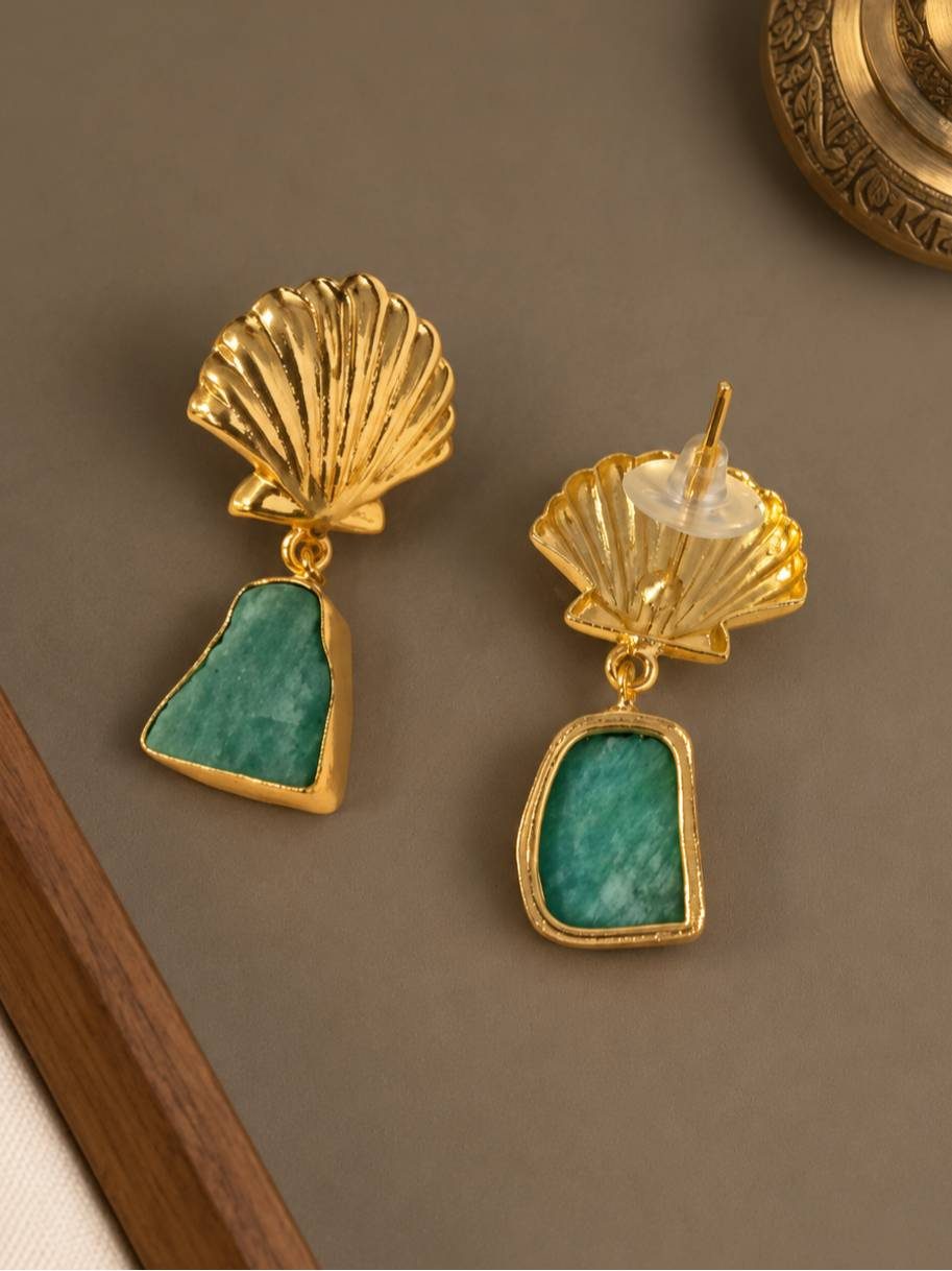 Close-up of gold shell stud earrings with teal green stone drops, reverse side visible