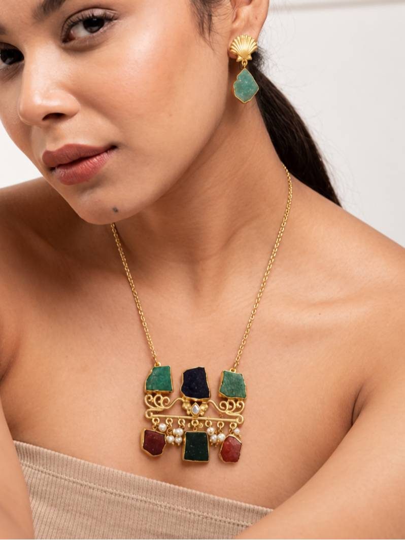 Model wearing gold-plated multicolour stone pendant necklace with teal shell earrings on bare neckline