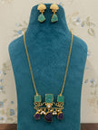Gold-plated necklace and earring set displayed on a teal velvet jewellery bust with green amazonite and purple amethyst stones