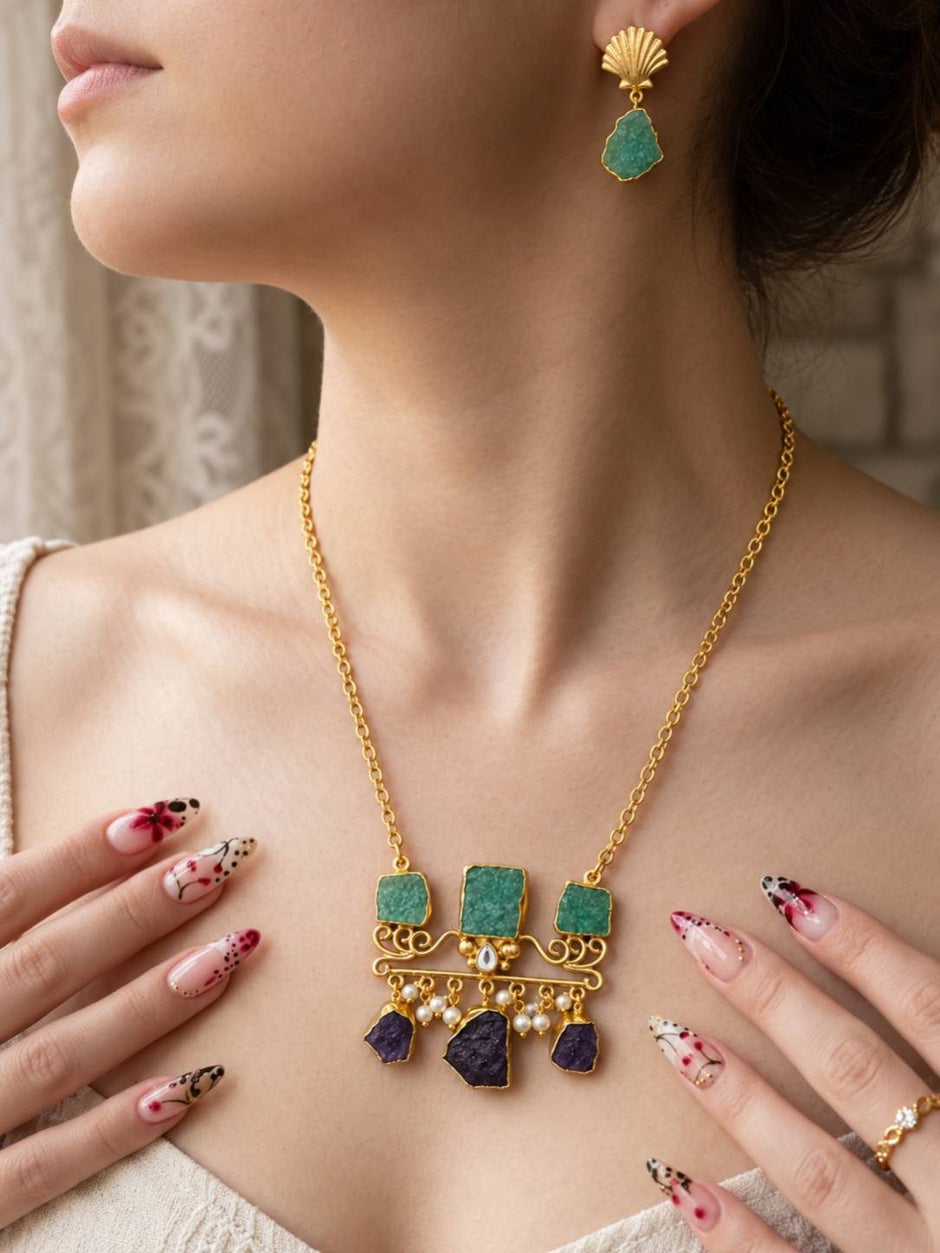 Woman wearing gold-plated amazonite statement necklace and seashell drop earrings with decorative nail art