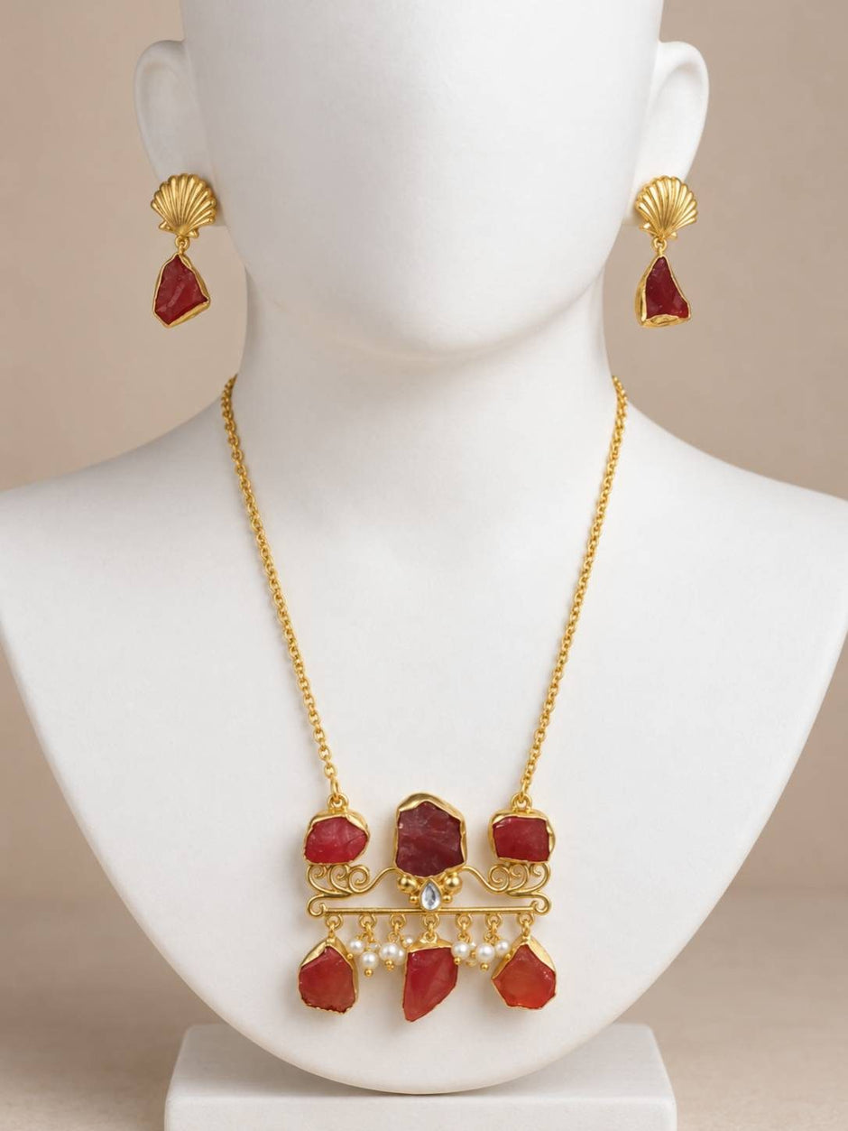 Gold-plated red stone necklace and shell earring set displayed on a white jewellery bust
